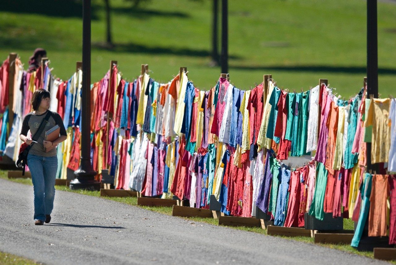 girl walking by t-shirts hung up